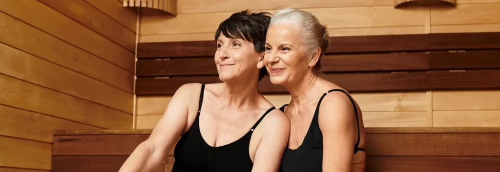 Two women enjoying relaxation and wellness in a sauna, embodying longevity and energy at Sisu Longevity Studio.