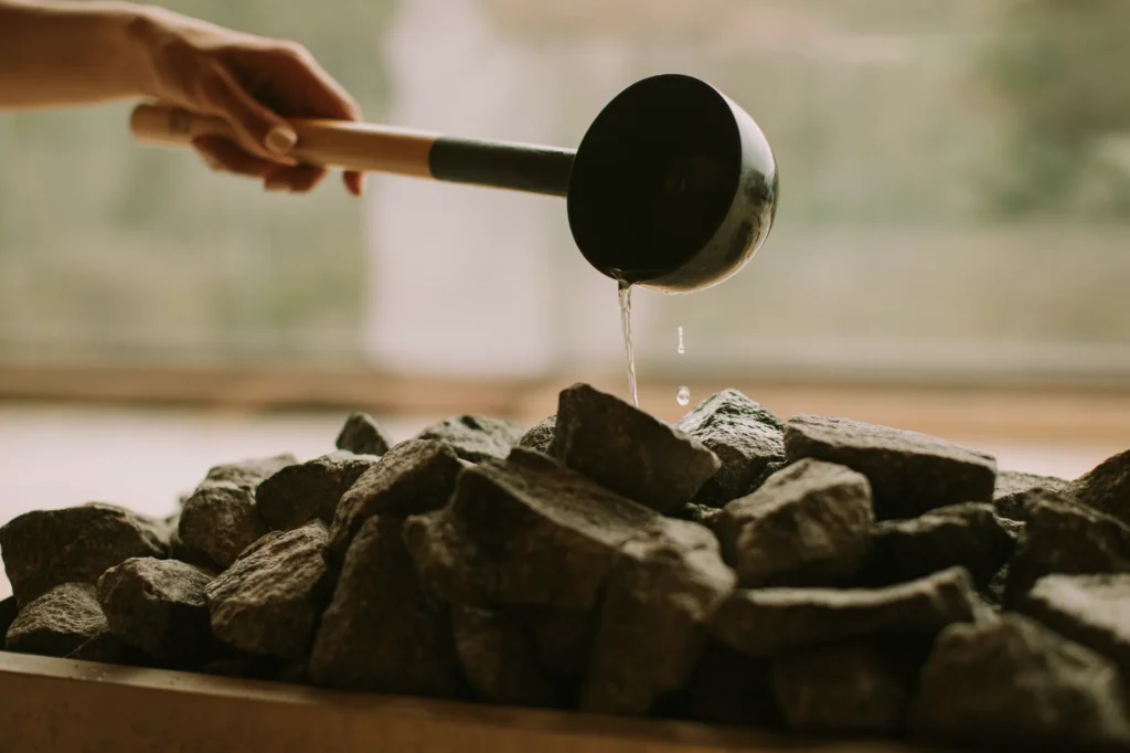 Contrast therapy sauna ladle pouring water on hot rocks at Sisu Longevity Studio Colorado Springs