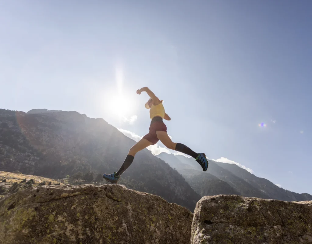 Athlete leaping across rocks embodies energy and resilience in nature.