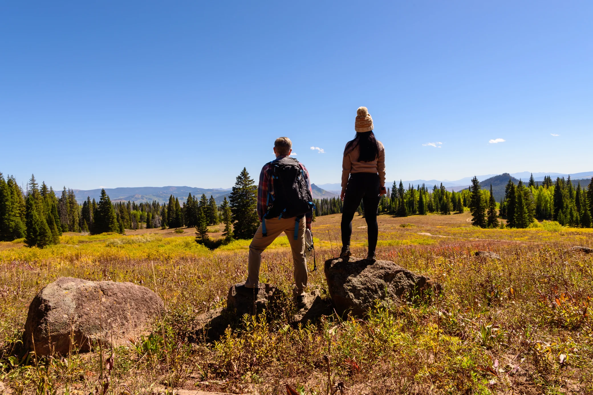 Two hikers standing on rocks enjoying a scenic view, embodying energy and resilience.