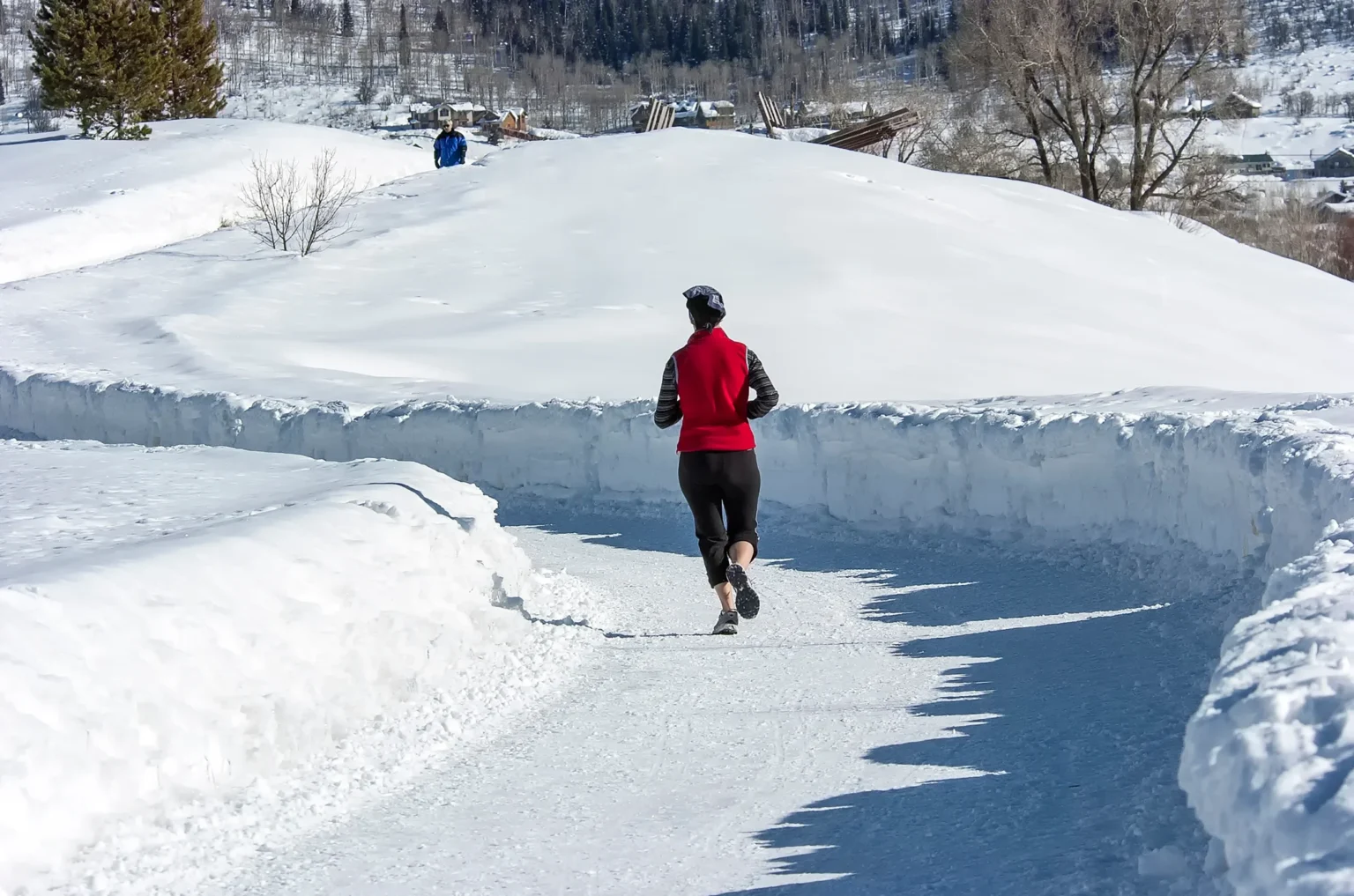 A person jogging on a snow-covered path, embodying energy and resilience in a winter landscape.