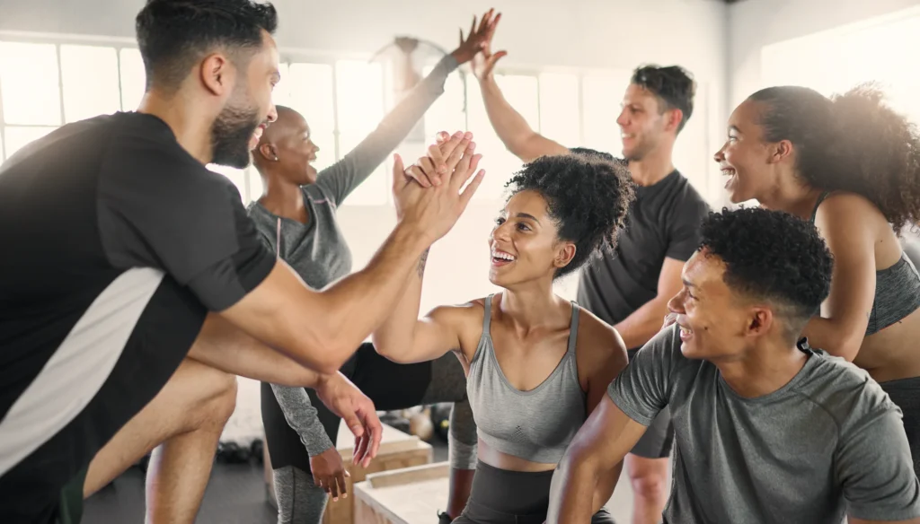 Group of people high-fiving and smiling, embodying energy and wellness.