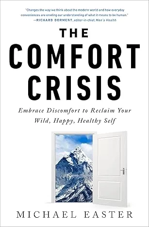 Book cover of "The Comfort Crisis" by Michael Easter, featuring an open door to a snowy mountain, relevant to themes of resi…