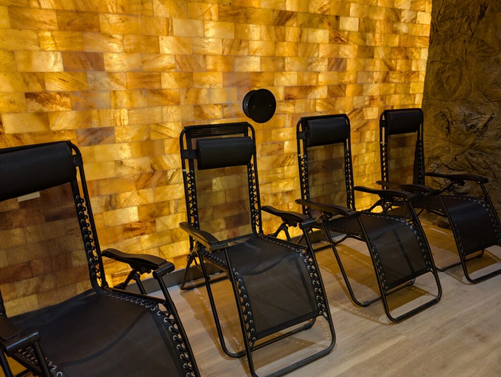 Backlit Himalayan salt wall and zero-gravity loungers in the salt cave at Sisu Longevity Studio in Colorado Springs